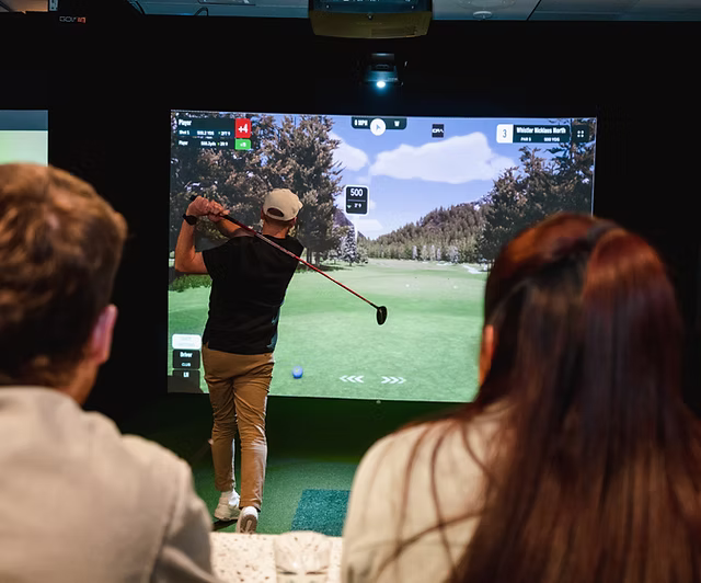 Golfers playing in a Shanky's Golf simulator bay